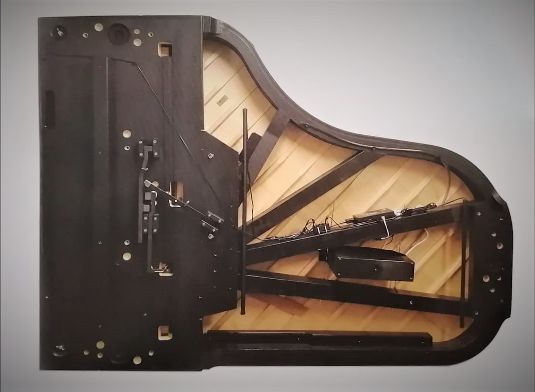 Installed Piano Life Saver under a grand piano, humidifier bar and wiring visible on the soundboard ribs